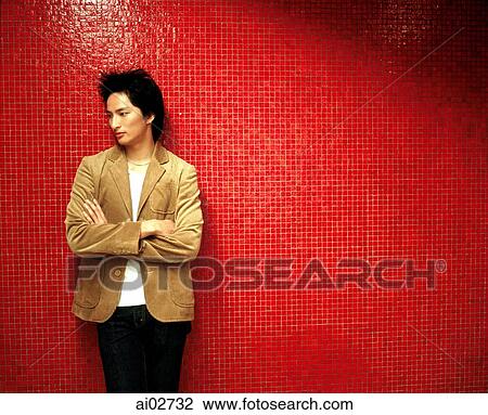 Young man in brown jacket leaning against orange/red background, looking away. View Large Photo Image Stock Image - Young man in brown jacket leaning against orange/red background, looking away.. Fotosearch