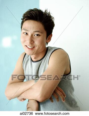 Young man leaning against rail smiling, blue/white background, portrait. View Large Photo Image Stock Photograph - Young man leaning against rail smiling, blue/white background, portrait.. Fotosearch