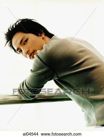 Young man leaning on rail, looking over shoulder. View Large Photo Image Picture - Young man leaning on rail, looking over shoulder.. Fotosearch