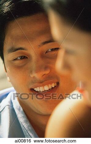 Stock Photograph - Young man looking at profile of young woman, smiling. Fotosearch
