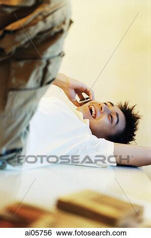 Stock Photograph - Young man lying on floor using cellular phone ( high grain). Fotosearch