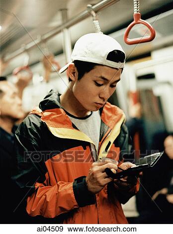 Stock Photo - Young man on train using PDA.. Fotosearch