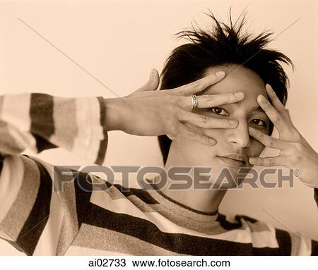 Young man peering through splayed fingers. View Large Photo Image Stock Image - Young man peering through splayed fingers.. Fotosearch