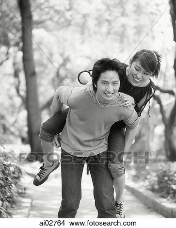 Young man piggybacking woman on nature path. View Large Photo Image Picture - Young man piggybacking woman on nature path.. Fotosearch