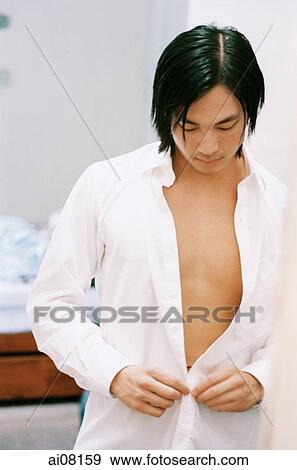Young man putting on white shirt. View Large Photo Image Stock Photo - Young man putting on white shirt.. Fotosearch