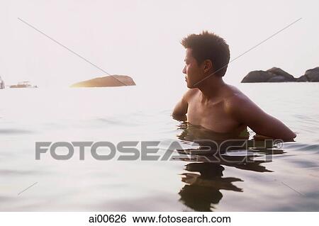 Young man standing in ocean, looking at horizon View Large Photo Image Stock Photograph - Young man standing in ocean, looking at horizon. Fotosearch