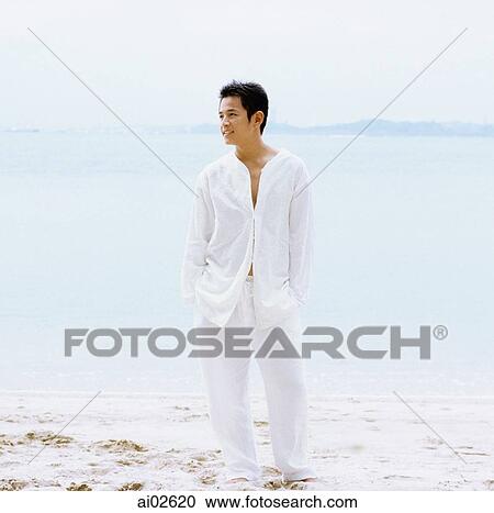 Young man standing on beach View Large Photo Image Stock Image - Young man standing on beach. Fotosearch