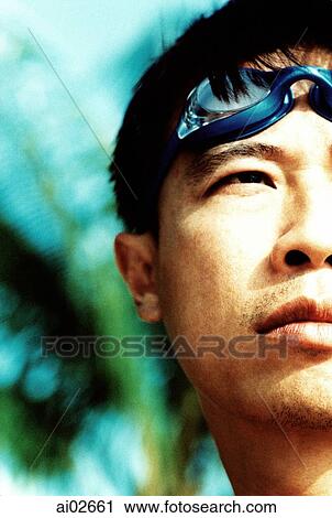 Stock Image - Young man with swimming goggles on head, half profile. Fotosearch