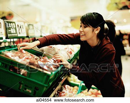 Young woman at supermarket choosing fruit. View Large Photo Image Picture - Young woman at supermarket choosing fruit.. Fotosearch