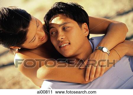 Young woman embracing young man from back, looking into each other's eyes View Large Photo Image Stock Image - Young woman embracing young man from back, looking into each other's eyes. Fotosearch