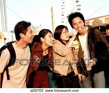 Young woman feeding fishballs to man at carnival while friends look on. View Large Photo Image Stock Image - Young woman feeding fishballs to man at carnival while friends look on.. Fotosearch
