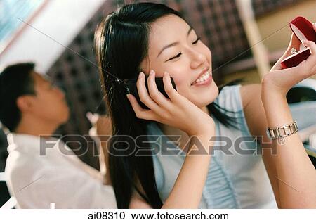 Young woman holding mobile phone and ring, looking, smiling. View Large Photo Image Stock Image - Young woman holding mobile phone and ring, looking, smiling.. Fotosearch