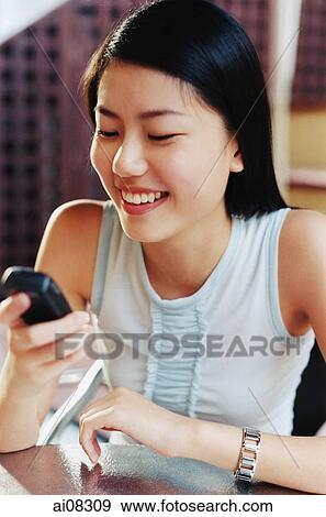 Young woman holding mobile phone, looking, smiling. View Large Photo Image Stock Photo - Young woman holding mobile phone, looking, smiling.. Fotosearch