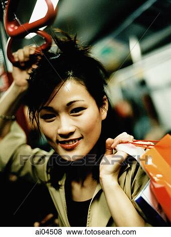 Young woman holding shopping bag standing in train. View Large Photo Image Stock Photo - Young woman holding shopping bag standing in train.. Fotosearch
