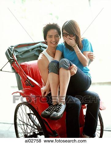 Stock Photo - Young woman in sunglasses sitting on lap of man on rickshaw.. Fotosearch
