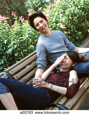 Young woman lying on bench with head on man's lap, nature in background. View Large Photo Image Stock Image - Young woman lying on bench with head on man's lap, nature in background.. Fotosearch