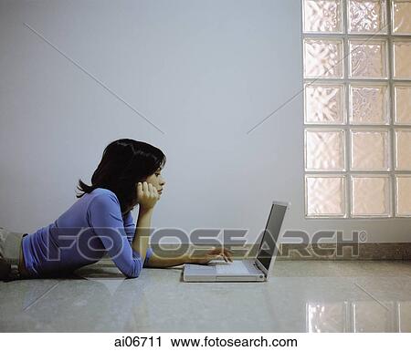 Young woman lying on floor looking at laptop monitor. View Large Photo Image Stock Image - Young woman lying on floor looking at laptop monitor.. Fotosearch