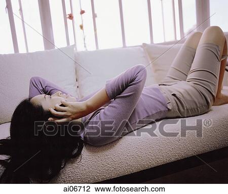 Young woman lying on sofa holding cellular phone. View Large Photo Image Stock Image - Young woman lying on sofa holding cellular phone.. Fotosearch
