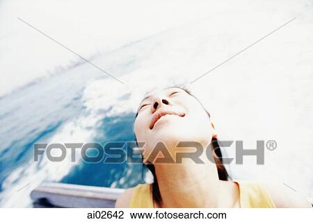 Young woman sitting at the back of a boat, looking up, sea in background View Large Photo Image Stock Image - Young woman sitting at the back of a boat, looking up, sea in background. Fotosearch