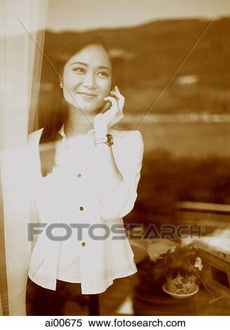 Young woman standing behind window, talking on cellular phone, reflection of skyline View Large Photo Image Stock Photography - Young woman standing behind window, talking on cellular phone, reflection of skyline. Fotosearch