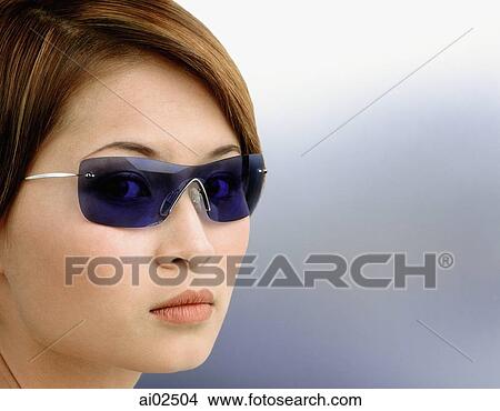 Young woman wearing blue tinted sunglasses, portrait View Large Photo Image Picture - Young woman wearing blue tinted sunglasses, portrait. Fotosearch