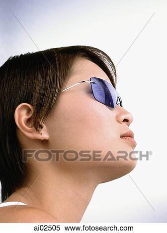 Young woman wearing blue tinted sunglasses, portrait View Large Photo Image Stock Photography - Young woman wearing blue tinted sunglasses, portrait. Fotosearch