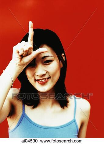 Young woman with finger and thumb in shape of "L" on forehead, red background. View Large Photo Image Stock Image - Young woman with finger and thumb in shape of "L" on forehead, red background.. Fotosearch