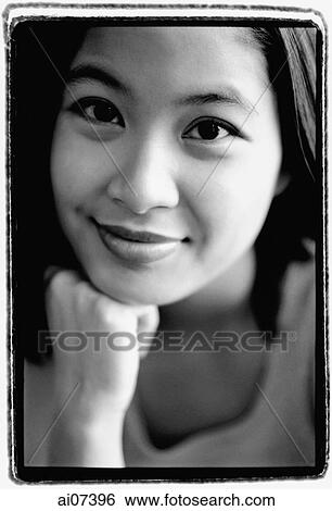 Stock Photograph - Young woman with hands on chin, smiling.. Fotosearch