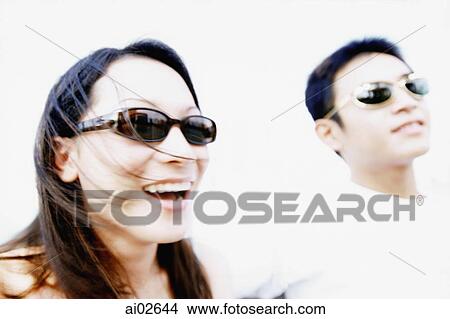 Young woman with sunglasses laughing, man in background View Large Photo Image Picture - Young woman with sunglasses laughing, man in background. Fotosearch