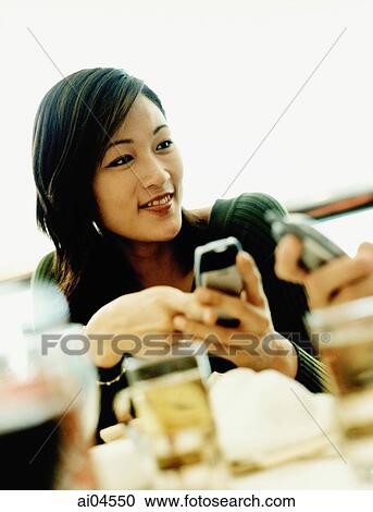 Young women holding cellular phone, looking off camera. View Large Photo Image Stock Image - Young women holding cellular phone, looking off camera.. Fotosearch