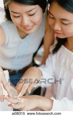 Stock Photography - Young women looking at ring on finger, smiling.. Fotosearch