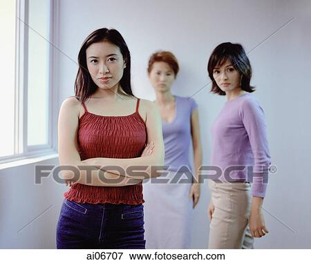 Stock Photo - Young women standing, arms crossed. Fotosearch