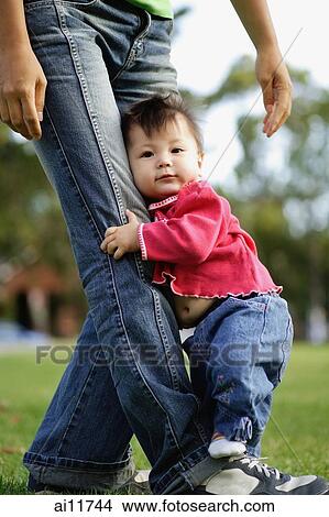 Baby girl holding on to her mother's leg. View Large Photo Image Picture - Baby girl holding on to her mother's leg.. Fotosearch