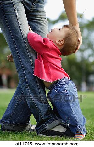 Baby girl holding on to her mother's leg, looking up View Large Photo Image Stock Photography - Baby girl holding on to her mother's leg, looking up. Fotosearch