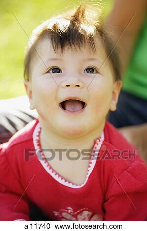 Stock Image - Baby girl looking up, smiling. Fotosearch