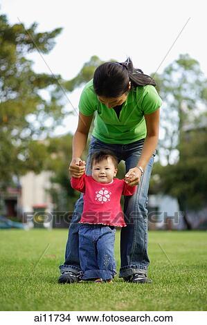 Baby girl standing, mother guiding her View Large Photo Image Picture - Baby girl standing, mother guiding her. Fotosearch