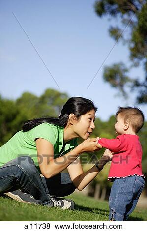 Stock Photo - Baby girl standing, mother holding her up. Fotosearch