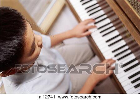 Boy sitting at piano, high angle view View Large Photo Image Stock Image - Boy sitting at piano, high angle view. Fotosearch