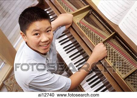 Boy sitting at piano, looking up at camera View Large Photo Image Stock Image - Boy sitting at piano, looking up at camera. Fotosearch