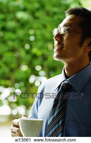 Businessman holding cup, looking away View Large Photo Image Stock Image - Businessman holding cup, looking away. Fotosearch
