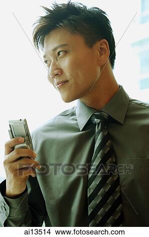 Businessman holding mobile phone, looking away View Large Photo Image Picture - Businessman holding mobile phone, looking away. Fotosearch