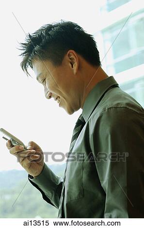 Stock Photography - Businessman holding mobile phone, text messaging. Fotosearch