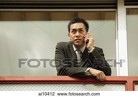Businessman on mobile phone, leaning on railing View Large Photo Image Stock Image - Businessman on mobile phone, leaning on railing. Fotosearch