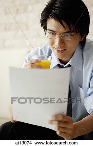 Businessman reading documents and drinking juice View Large Photo Image Picture - Businessman reading documents and drinking juice. Fotosearch