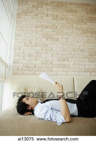 Businessman reading documents, lying on sofa View Large Photo Image Stock Photography - Businessman reading documents, lying on sofa. Fotosearch