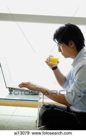 Businessman using laptop and drinking orange juice View Large Photo Image Stock Photo - Businessman using laptop and drinking orange juice. Fotosearch
