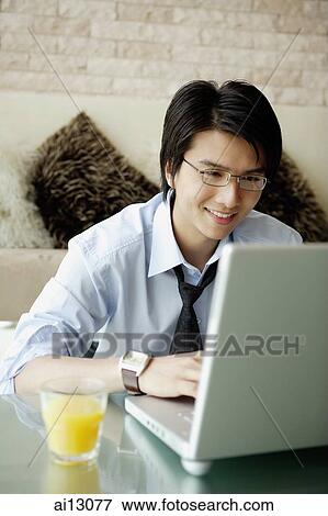 Businessman using laptop, glass of orange juice next to him View Large Photo Image Stock Photo - Businessman using laptop, glass of orange juice next to him. Fotosearch