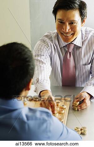 Stock Photograph - Businessmen playing chess, one smiling at the other. Fotosearch