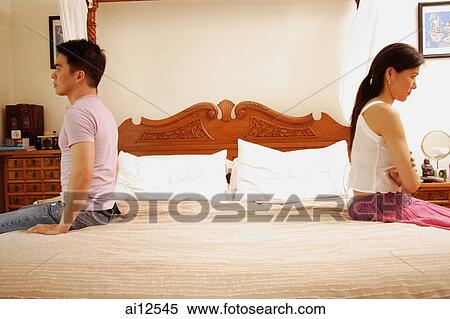 Stock Photography - Couple apart at the edge of bed. Fotosearch