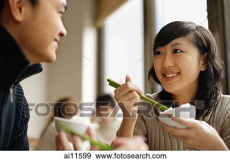 Couple at a Chinese restaurant, eating with chopsticks View Large Photo Image Stock Photo - Couple at a Chinese restaurant, eating with chopsticks. Fotosearch